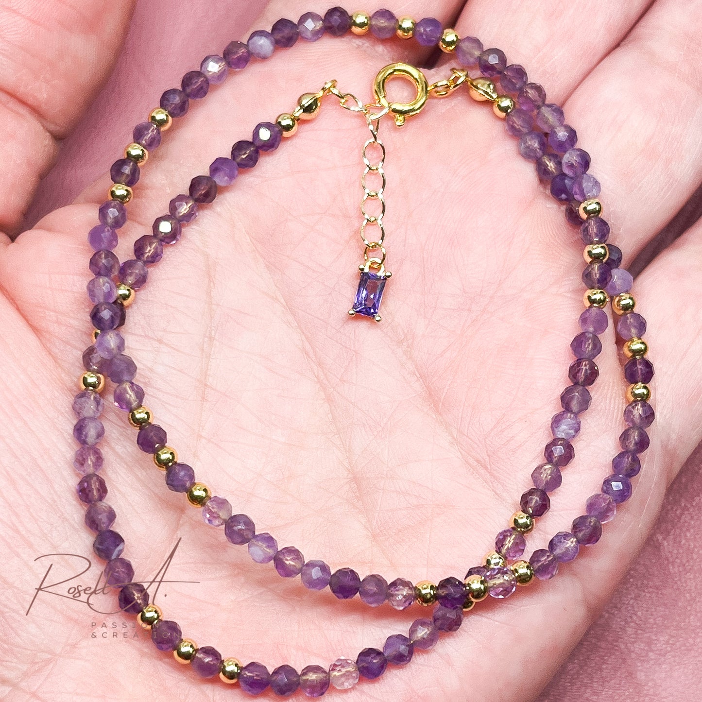 Detailansicht der Amethyst-Halskette in einer Hand gezeigt mit Fokus auf den violetten Farbverlauf der facettierten Perlen
