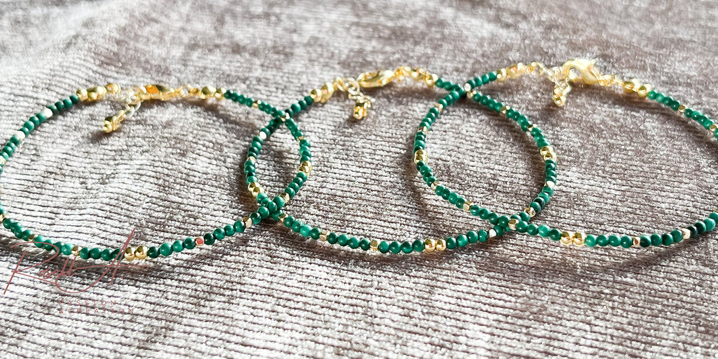 Armband mit intensiven grünen Malachitperlen bei Tageslicht auf glänzendem silberfarbenem Samtstoff fotografiert