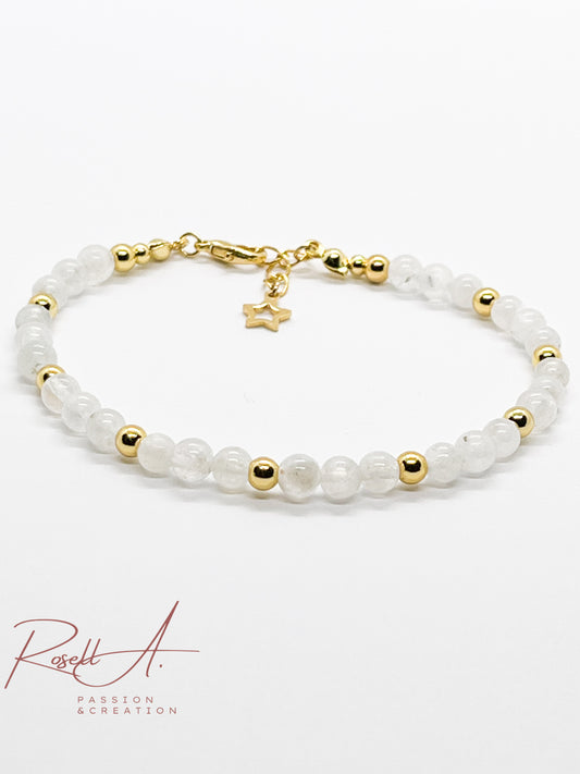 Zartes Armband mit weißen Peristeritperlen und goldenen Elementen schräg fotografiert auf weißem Hintergrund.